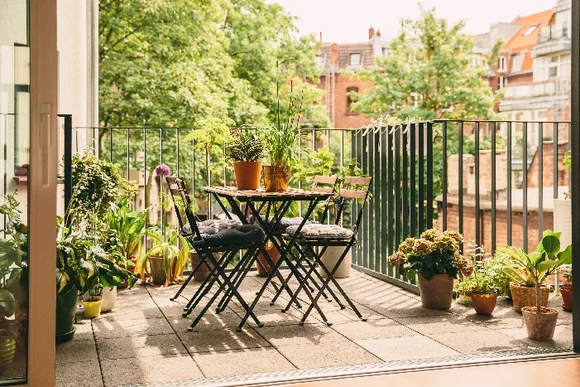Sonniger Balkon mit Pflanzen und Bistrotisch
